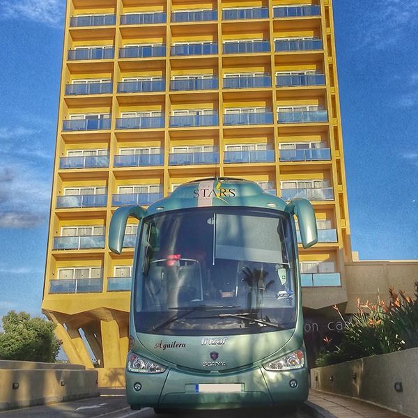 Un autobús verde con la palabra Irizar en el frente está estacionado frente a un edificio alto.