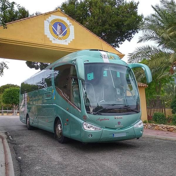 Un autobús verde está estacionado frente a un edificio amarillo que dice estrellas.