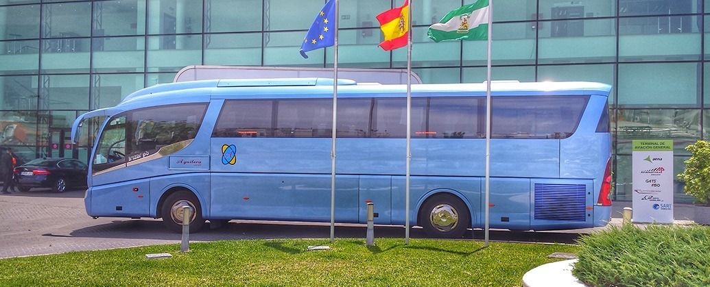 Un autobús azul está estacionado frente a un edificio.