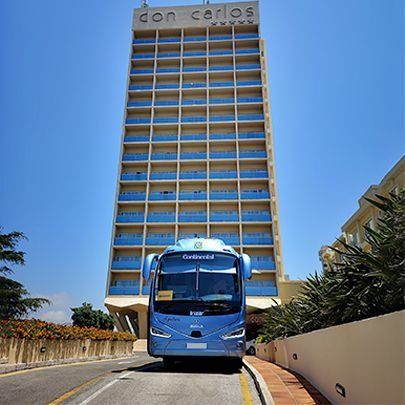 Un autobús azul está estacionado frente a un edificio que dice don carlos