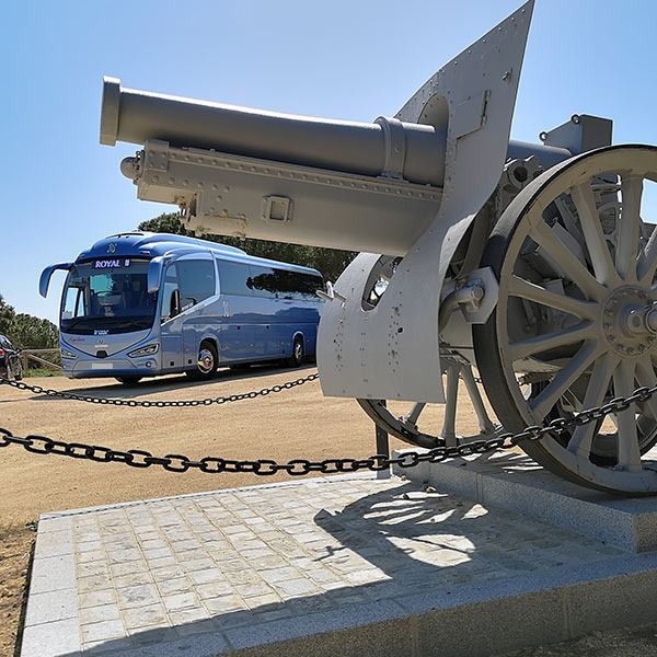 Un autobús azul está estacionado frente a un cañón.
