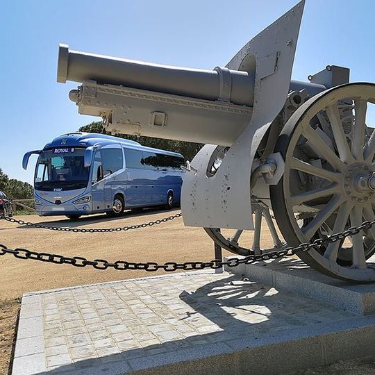 Un autobús azul está estacionado frente a un cañón.