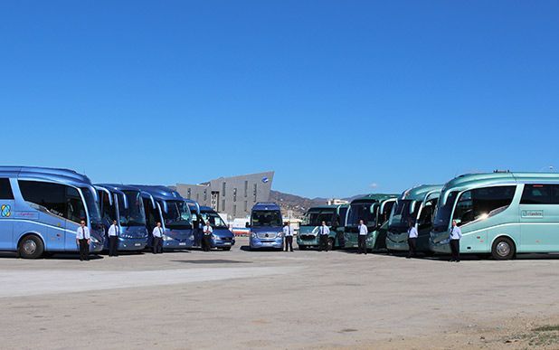 Una fila de autobuses están estacionados en un estacionamiento.