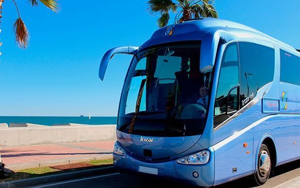 Un autobús azul está estacionado al costado de la carretera cerca del océano.