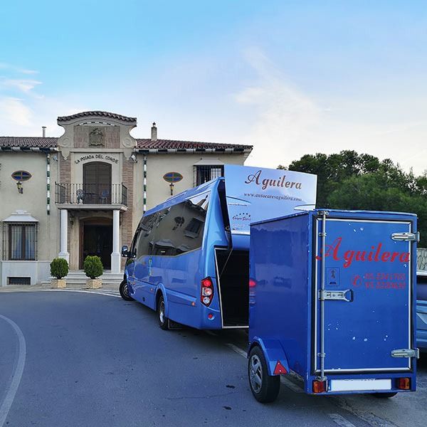 Un autobús azul tira de un remolque que dice aquilera