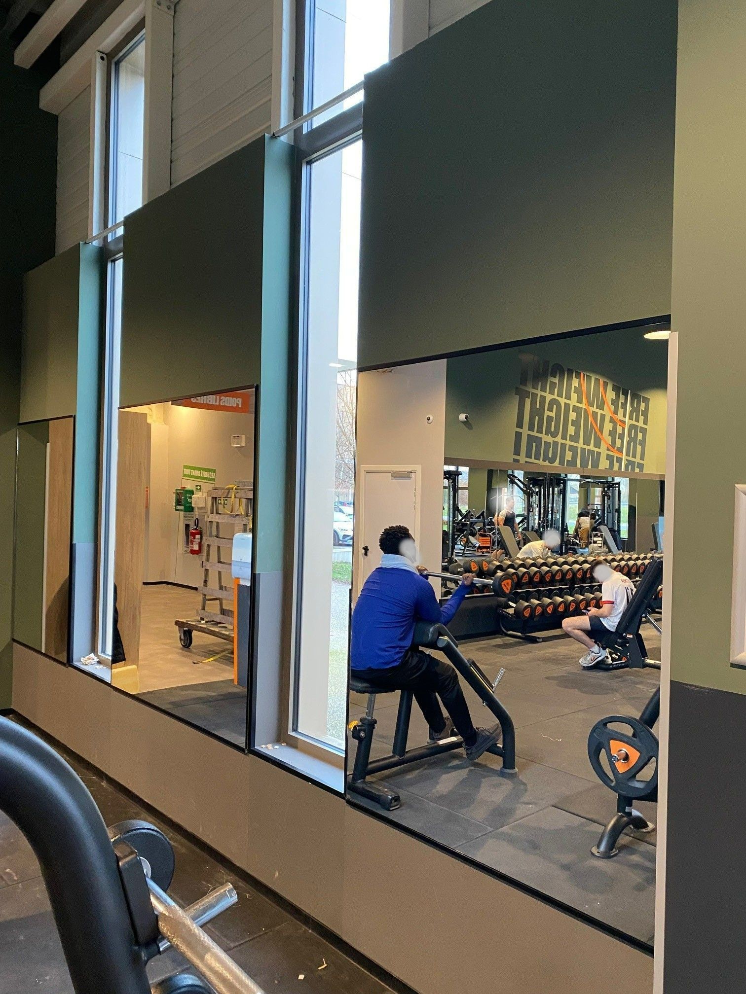 Trois grands miroirs installés sur le mur d'une salle de sport