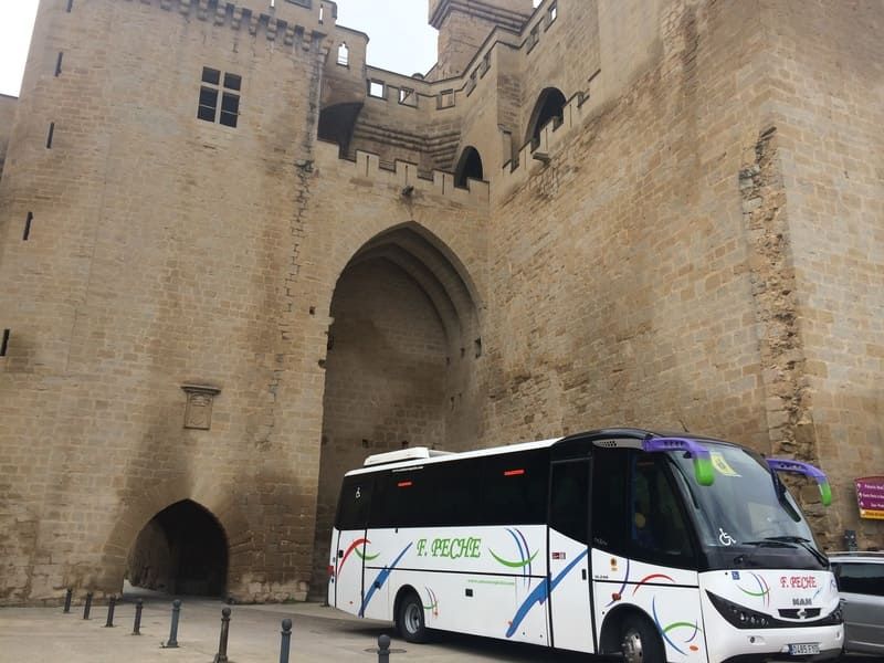 Un autobús blanco está estacionado frente a un castillo.