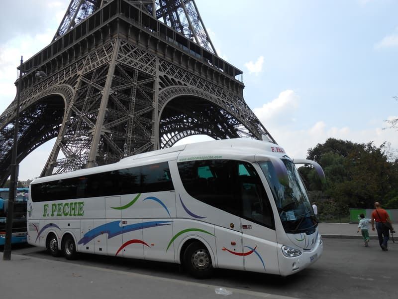 Un autobús blanco de F. Peche está estacionado frente a la Torre Eiffel.