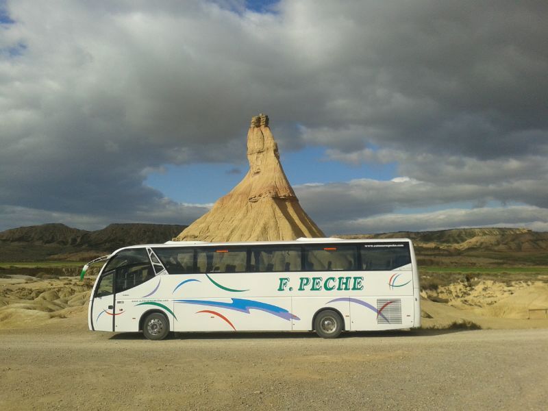 Un autobús blanco de F. Peche está estacionado en el desierto.