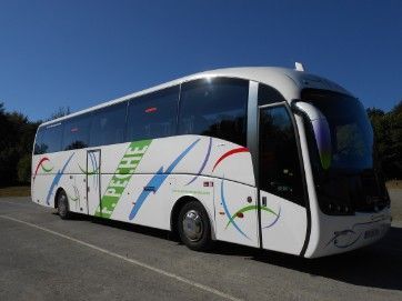 Un autobús blanco y verde está estacionado en un estacionamiento.