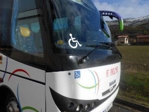Un autobús con un cartel de discapacitados en el parabrisas está estacionado al costado de la carretera.