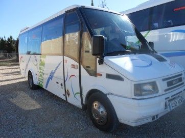 Un autobús blanco está estacionado en un estacionamiento al lado de otro autobús.