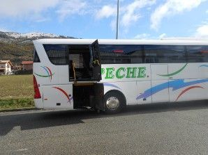 Un autobús blanco con la puerta abierta está estacionado al costado de la carretera.
