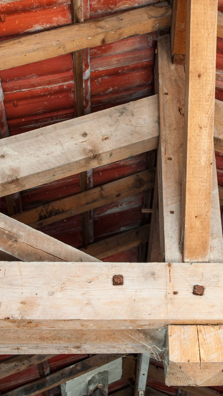 Charpente en bois contre un toit de tuiles rouges. Gros plan sur des poutres assemblées en angle.