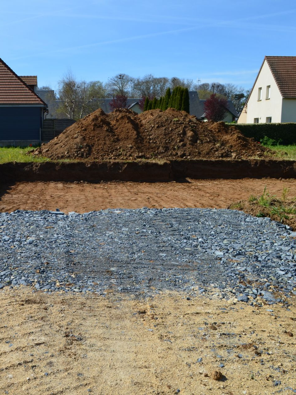 Un ouvrier répand du béton à la pelle sur un chantier de construction.