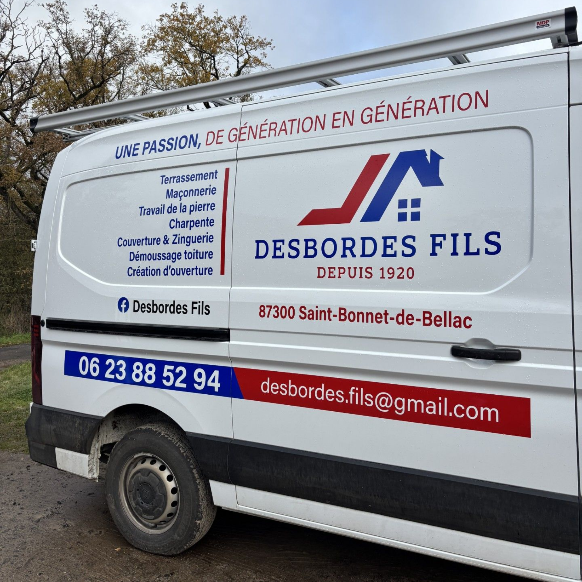 Camion plateau blanc stationné sur un chemin de terre à côté d'un bâtiment et d'arbres.