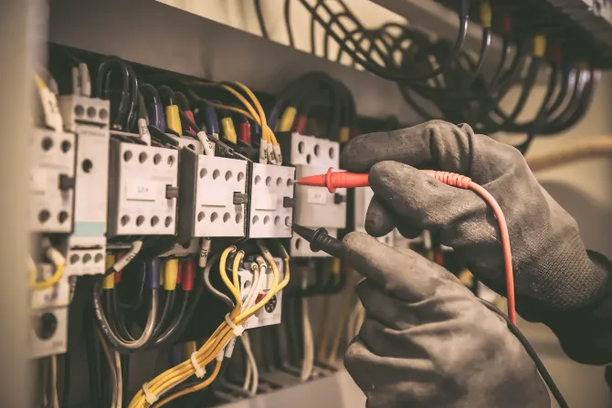 Un electricista está trabajando en una caja eléctrica con un multímetro.