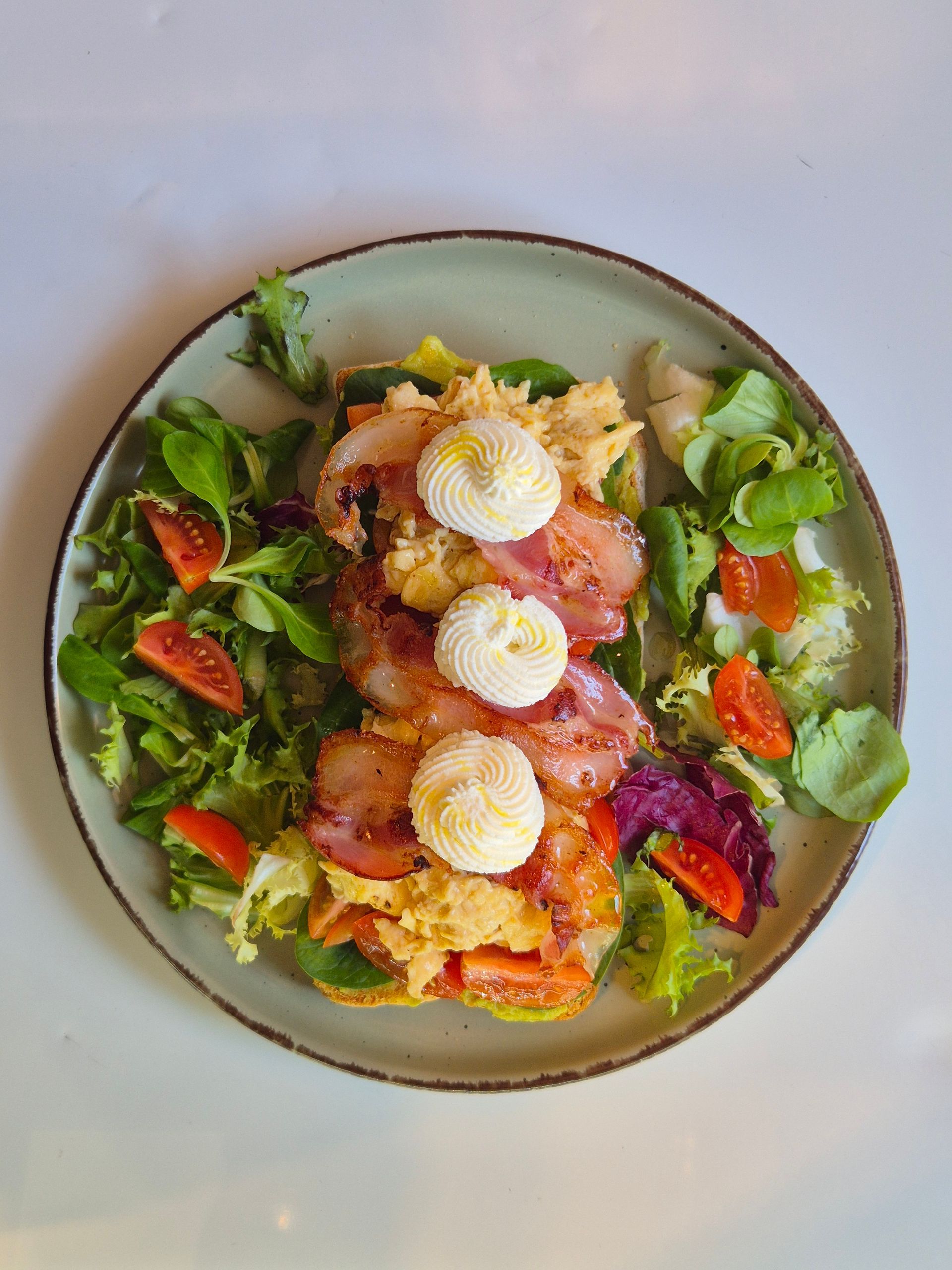 Ensalada con verduras, tomates, aguacate y huevo en rodajas en un plato redondo.
