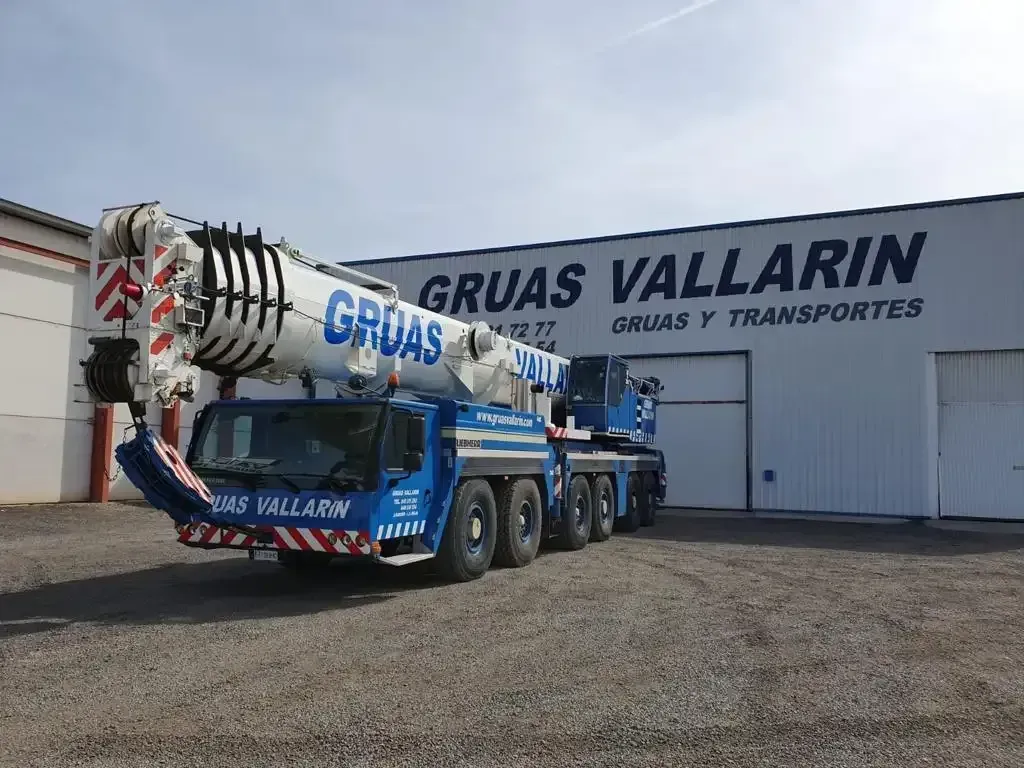 Una gran grúa está estacionada frente a un edificio.