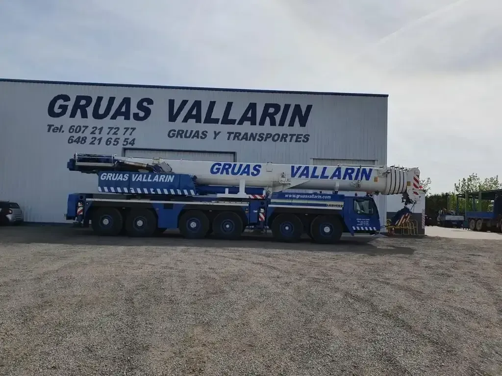 Una grúa está estacionada frente a un edificio que dice gruas vallarin