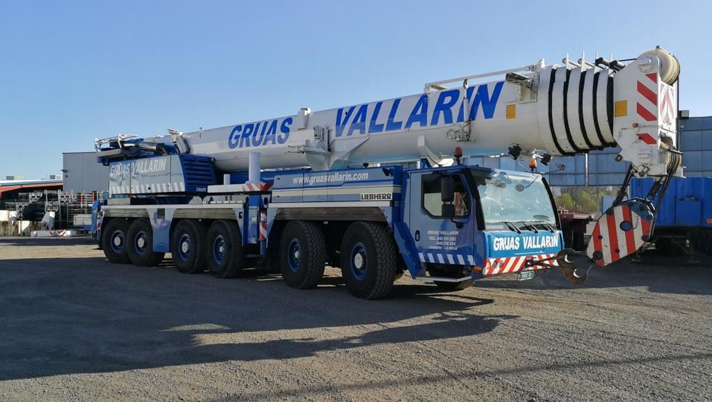 Un gran camión grúa está estacionado en un lote de grava.