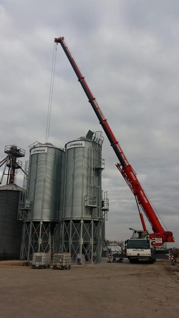 Una gran grúa roja está levantando algo delante de un edificio.