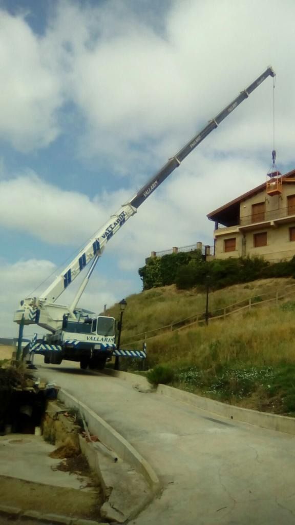 Una gran grúa está sentada al costado de una carretera al lado de una casa.