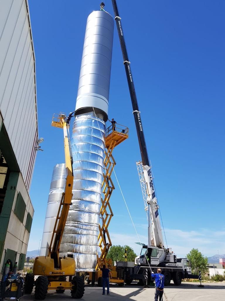 Un gran cilindro de metal está siendo levantado por una grúa.