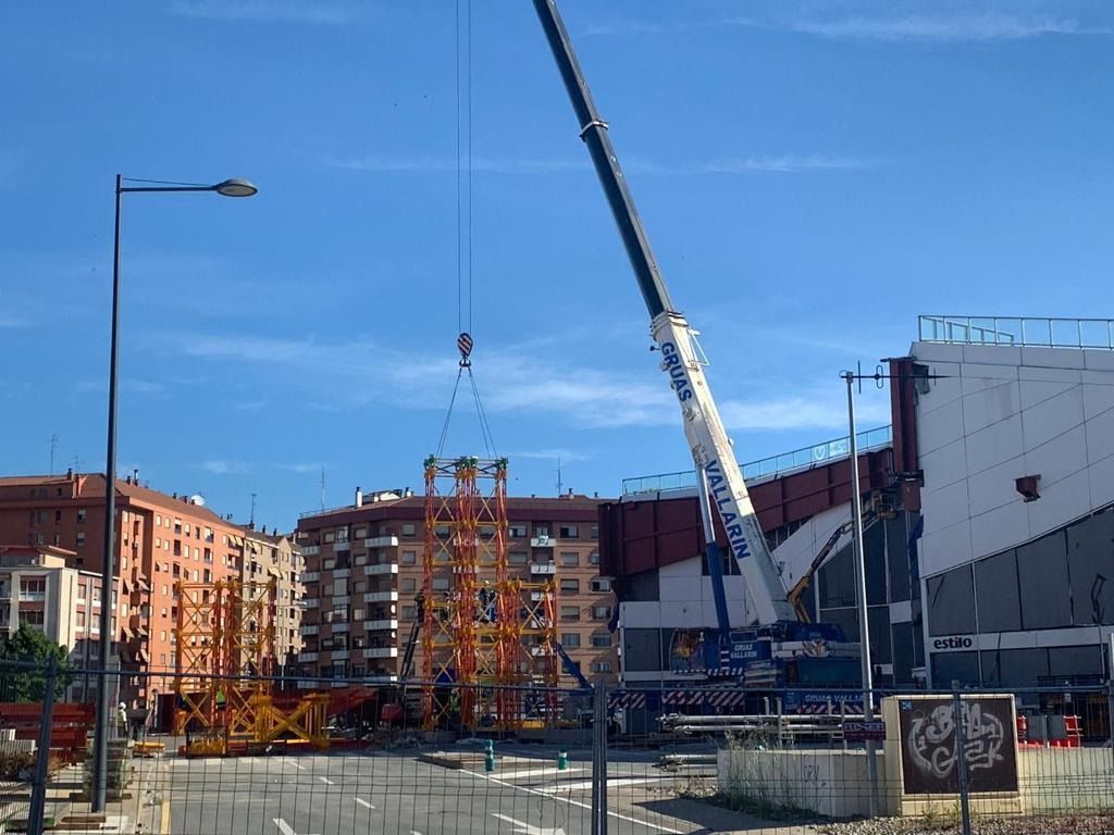 Una gran grúa está levantando una torre en una ciudad.