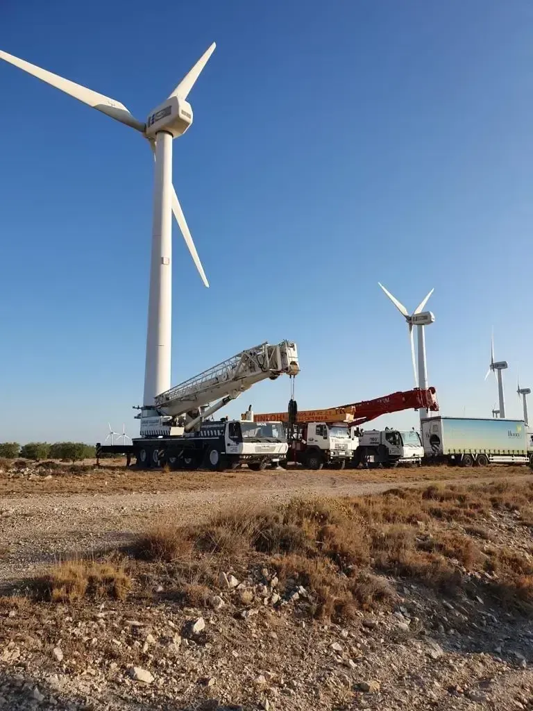 Una grúa está situada delante de un aerogenerador.