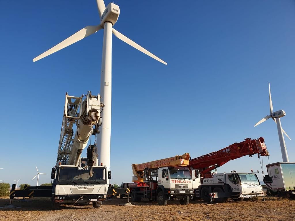 Un grupo de camiones está estacionado frente a un aerogenerador.
