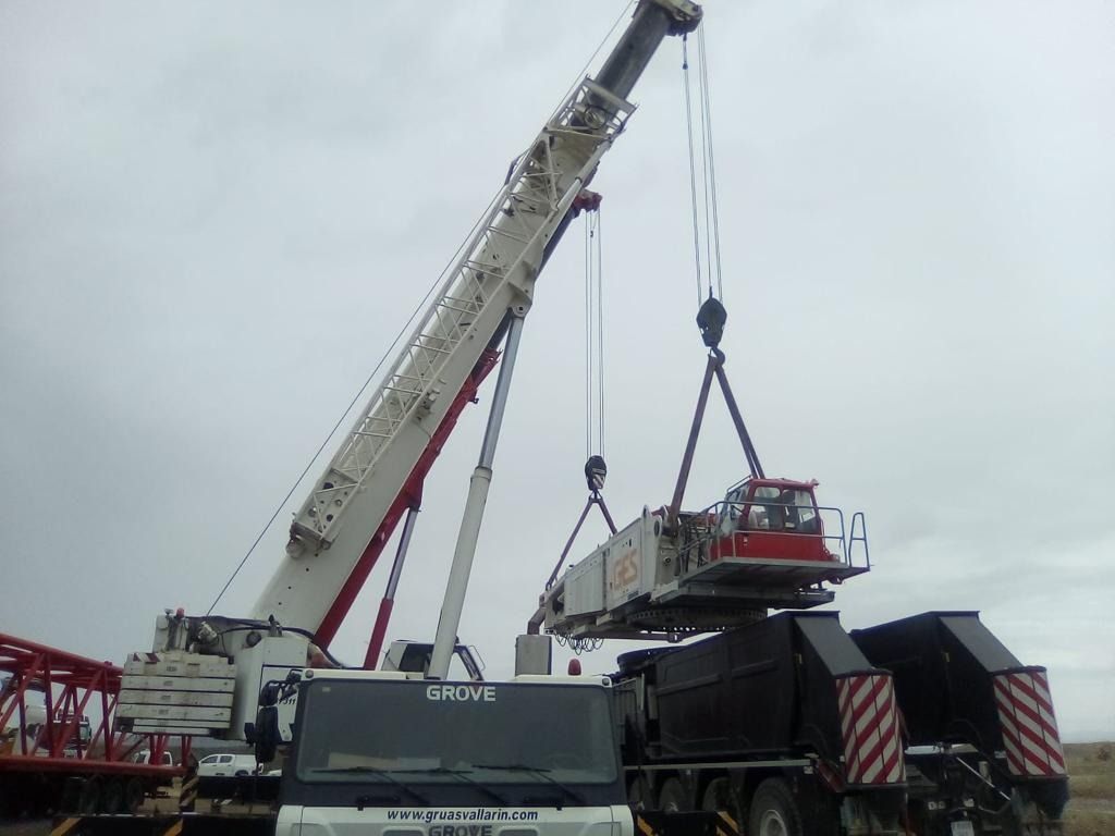 Una grúa grande está levantando un camión en un campo