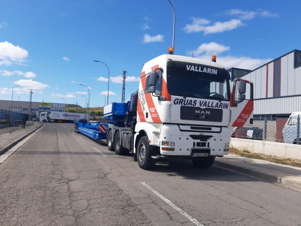 Un camión grande circula por una carretera al lado de un edificio.