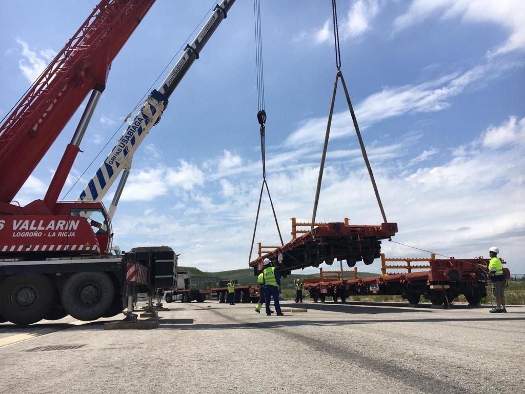 Una grúa roja está levantando una gran pieza de equipo