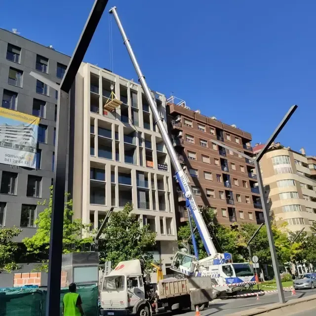 Un camión con una grúa acoplada está estacionado frente a un edificio.