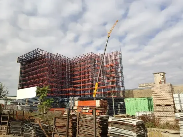 Un gran edificio en construcción con una grúa delante de él.