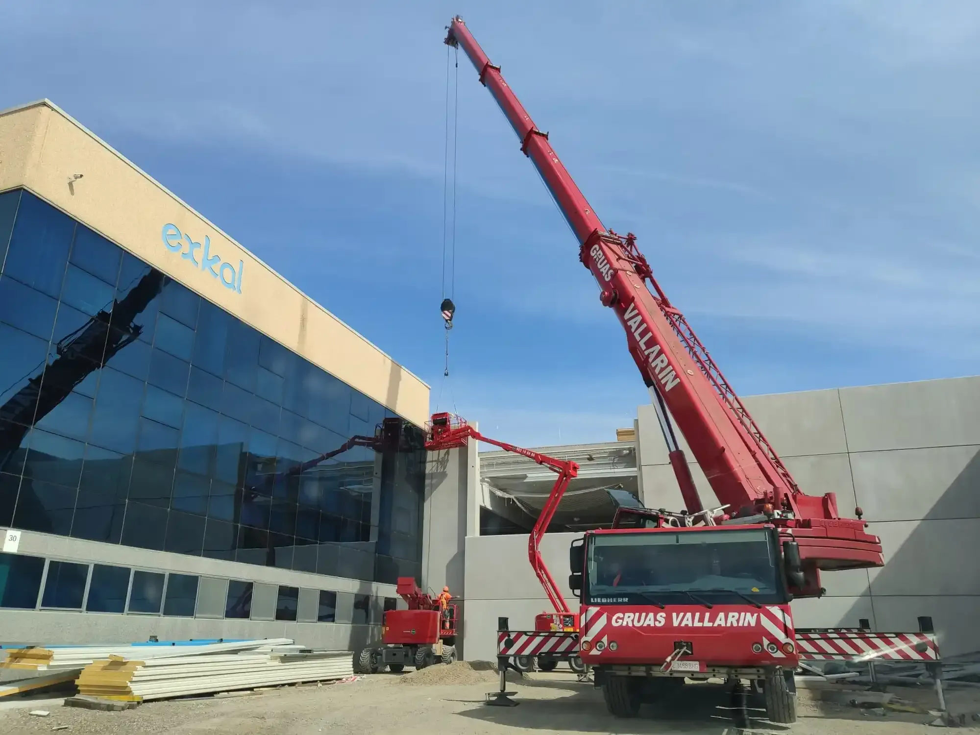 Una gran grúa roja está estacionada frente a un edificio