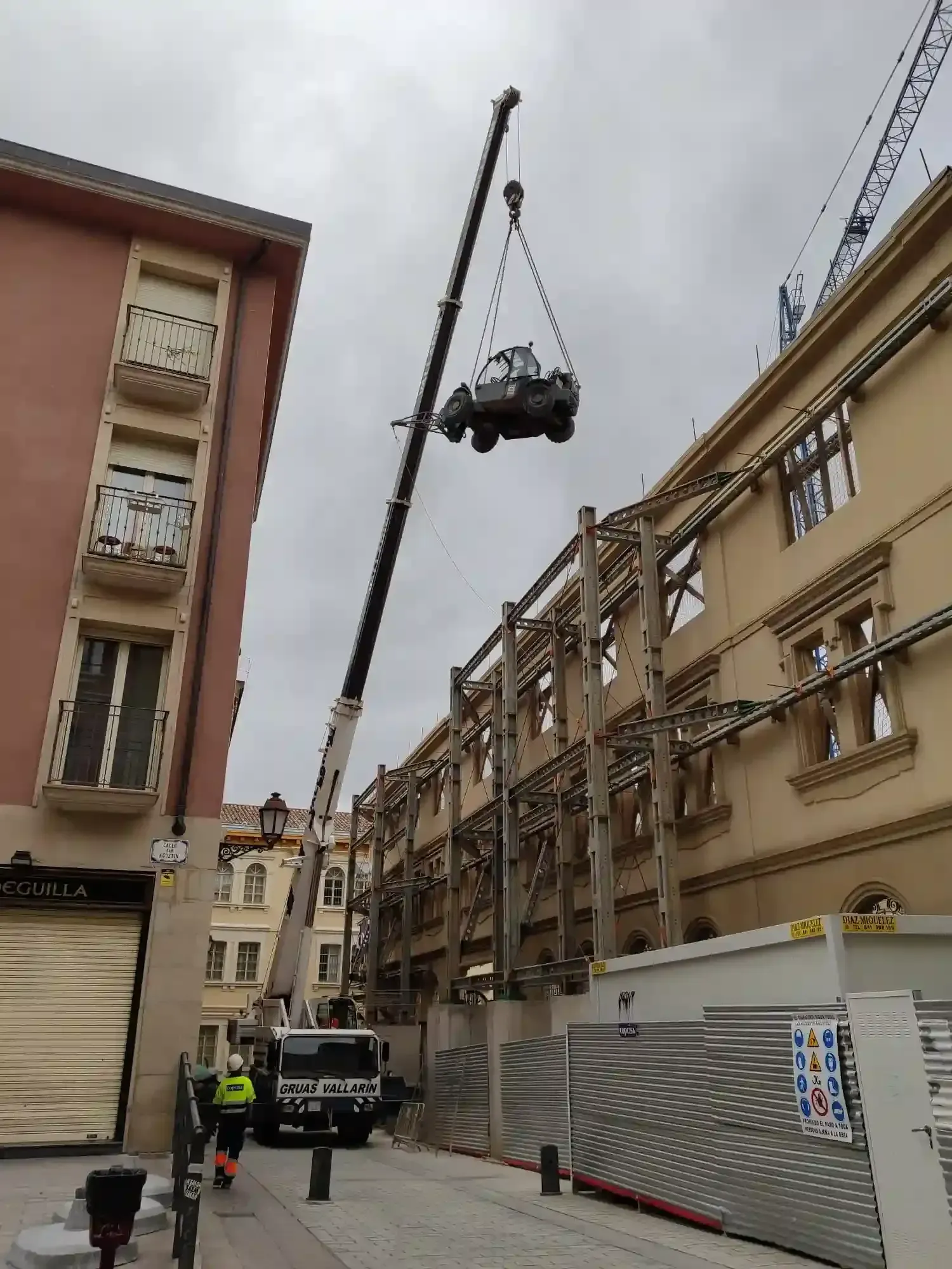 Una grúa está levantando un coche sobre un edificio.