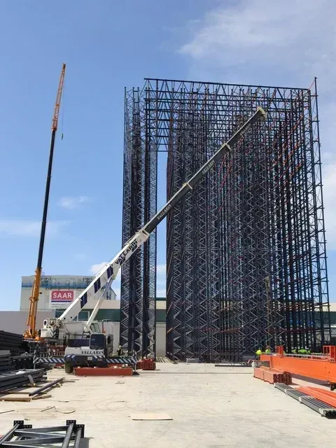 Una grúa está levantando una estructura grande en un sitio de construcción.