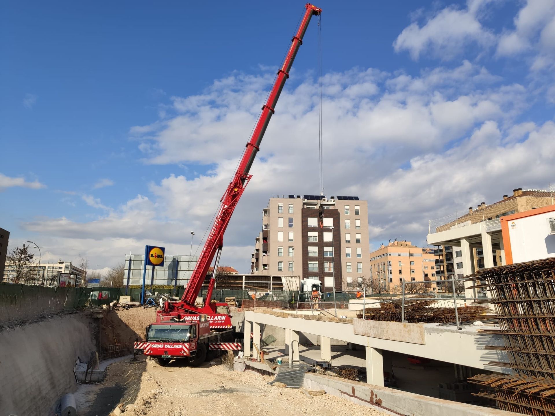 Una grúa roja está levantando una estructura de hormigón en un sitio de construcción.