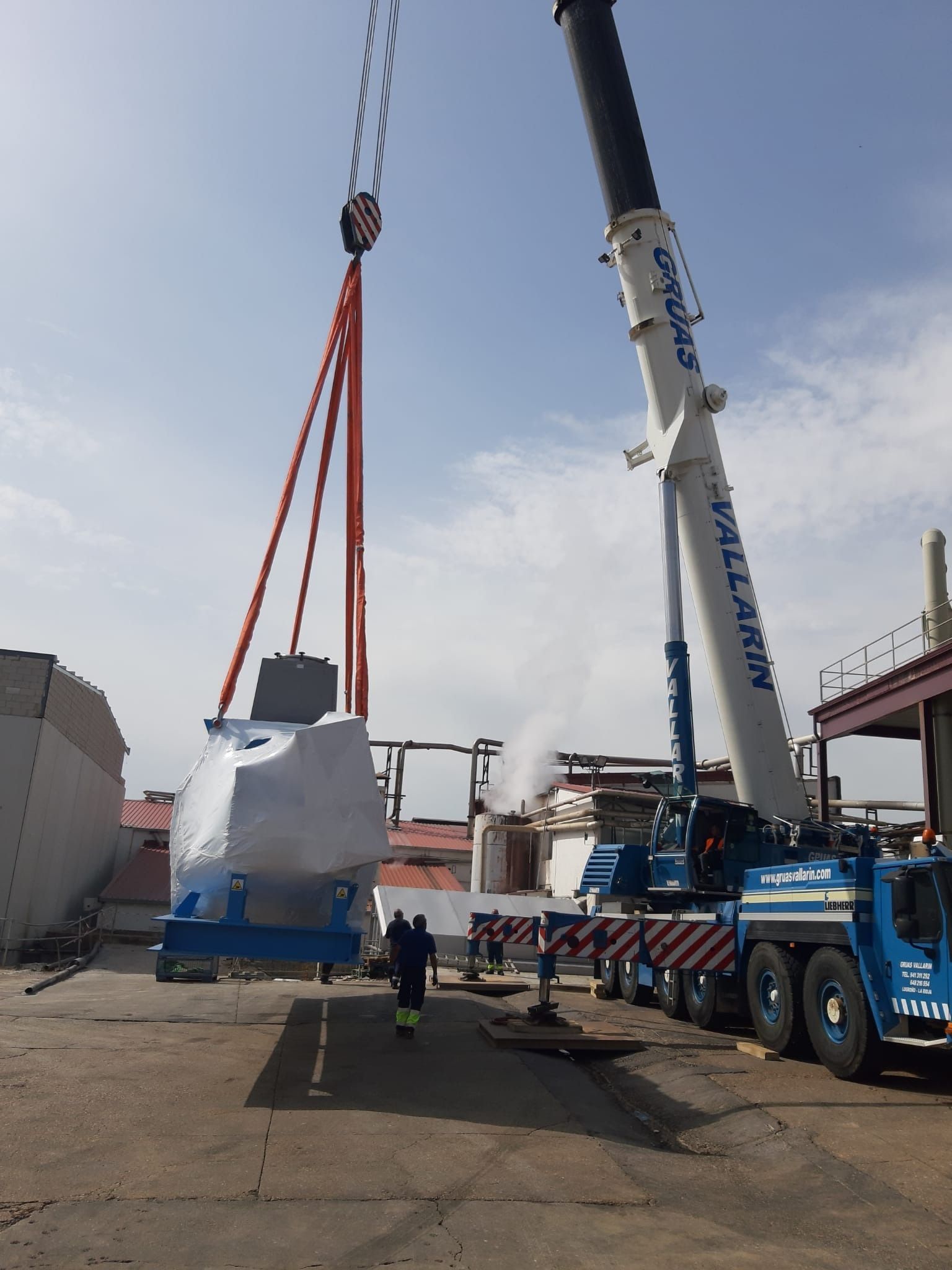 Una grúa grande está levantando un objeto grande en un estacionamiento.