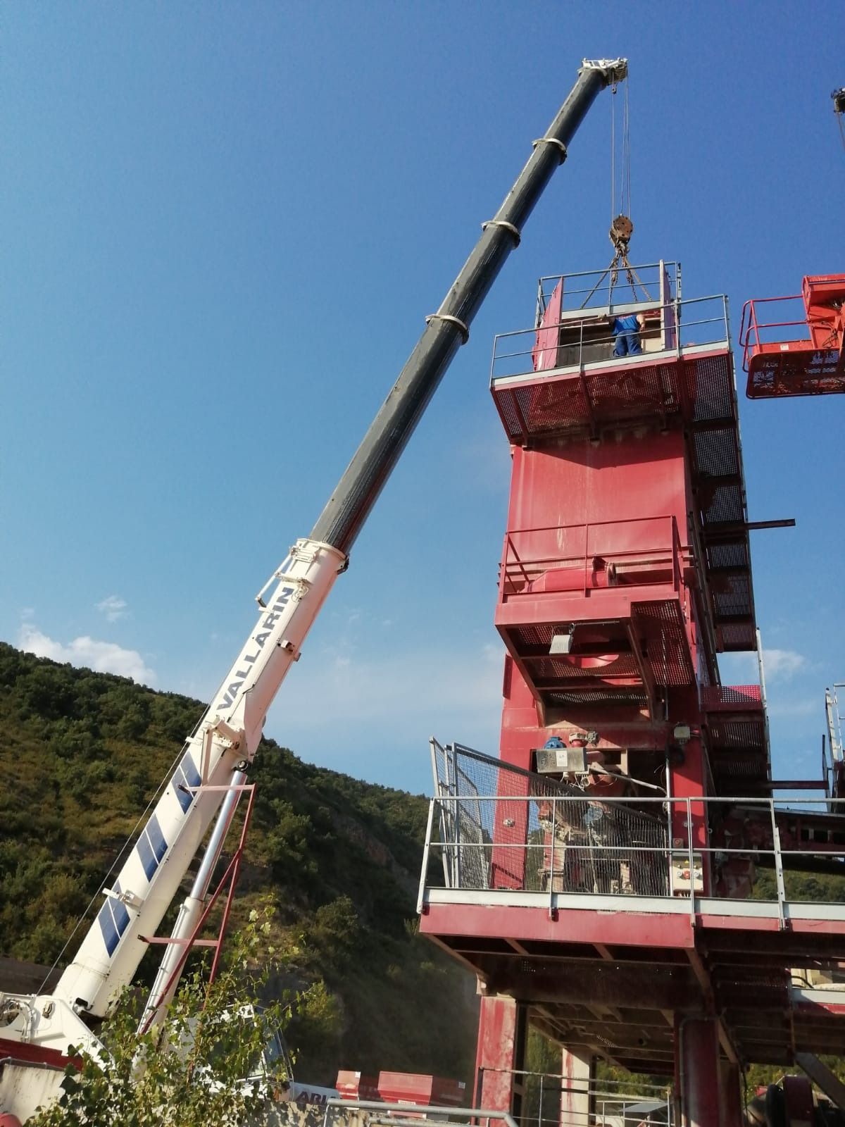 Una gran grúa está levantando un edificio rojo