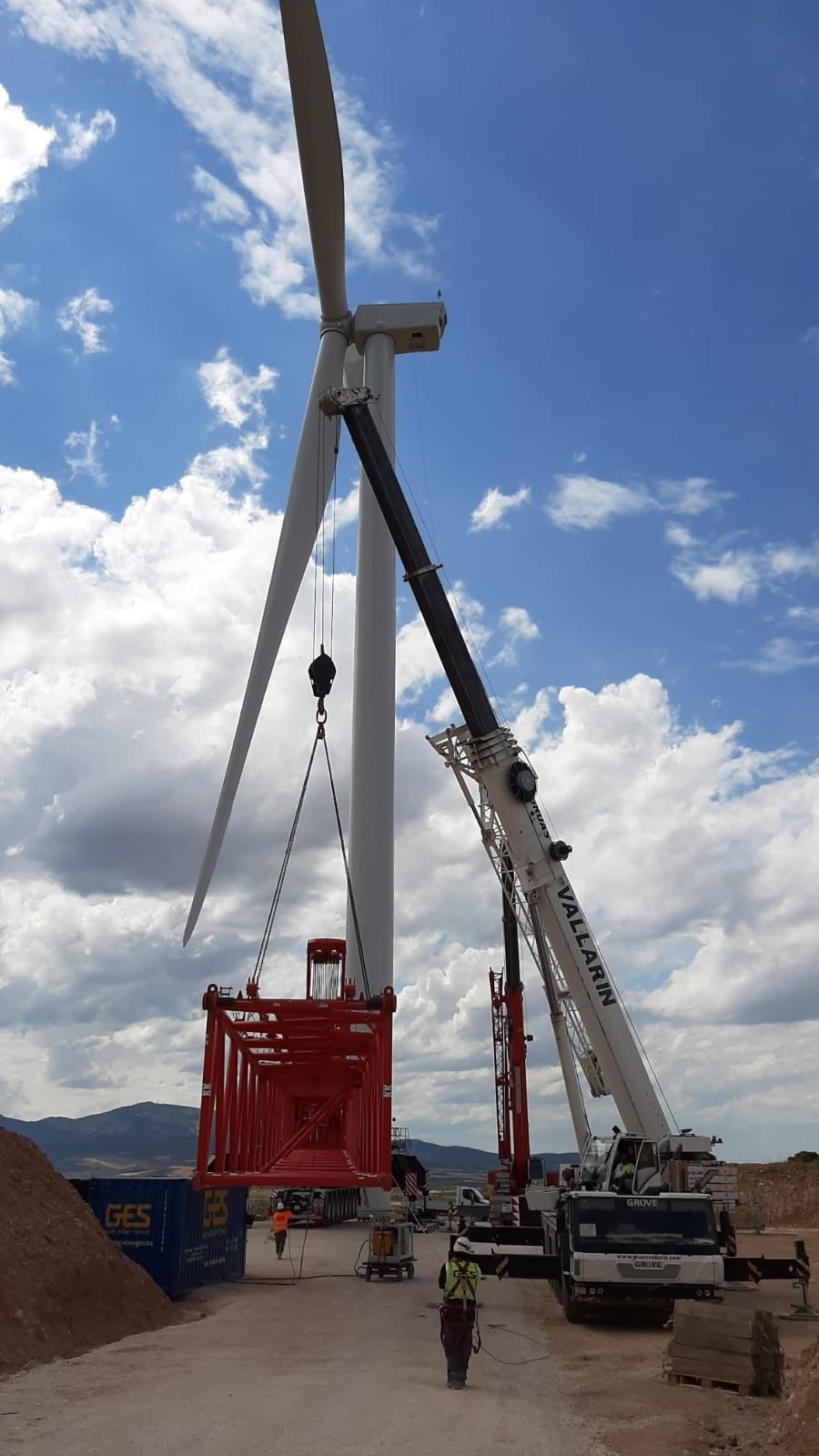 Una gran turbina eólica está siendo levantada por una grúa.