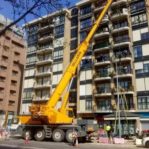 Una grúa amarilla está estacionada frente a un edificio alto.