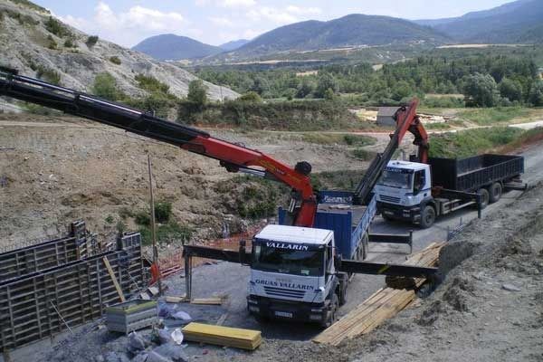 Una grúa está levantando un camión en un camino de tierra.