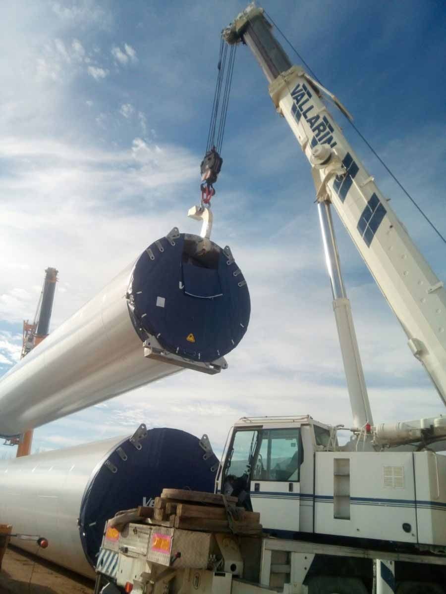 Una grúa está levantando un gran tubo azul y blanco.
