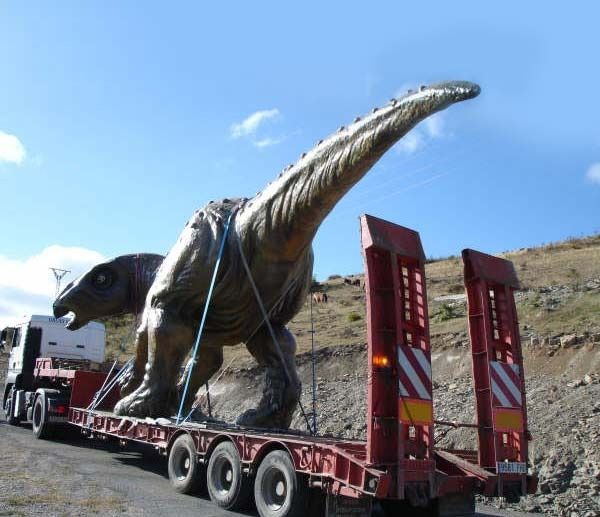 Una estatua de un dinosaurio está siendo transportada en un remolque.