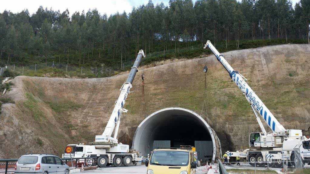 Un camión amarillo está estacionado frente a un túnel en construcción.