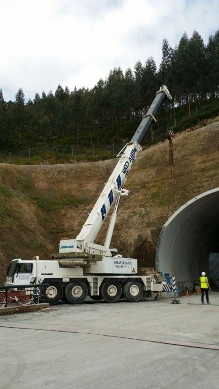 Un gran camión blanco con una grúa acoplada está estacionado frente a un túnel.