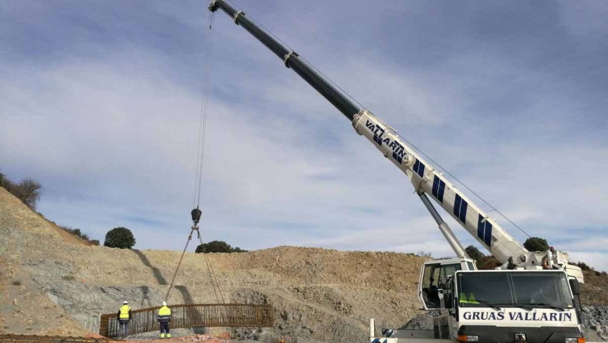 Se está utilizando una grúa grande para levantar una valla en una cantera.